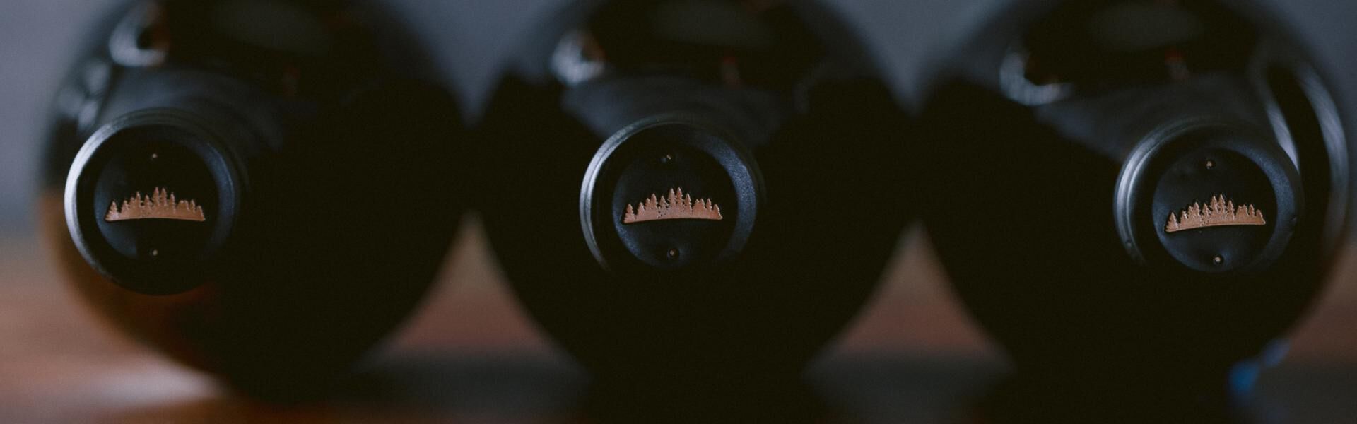 Three bottles of wines on their side with a view of their caps